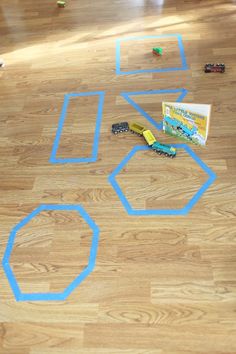 a child's drawing on the floor with blue tape and construction toys around it