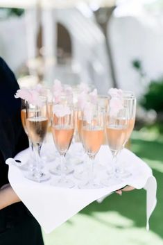 a woman holding a tray with champagne glasses on it