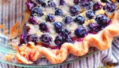 a blueberry pie is on a glass plate