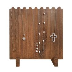 a wooden stand with several necklaces on it and a cross hanging from the top