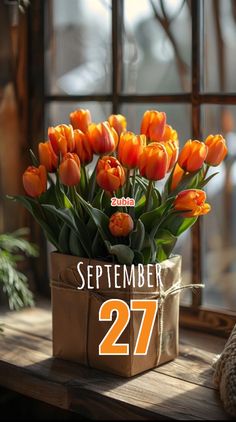 a vase filled with orange tulips sitting on top of a wooden table