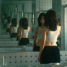 a woman standing in front of a bathroom mirror looking at herself in the mirror with her back to the camera