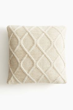 a white pillow with an intricate design on it's back and the front is made out of knitted fabric