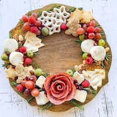 a wreath made out of cheeses, crackers and berries on a wooden board