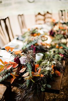 a long table with flowers and greenery on it