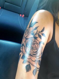 a woman's arm with a rose tattoo on it, sitting in a car