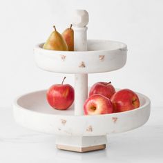 two trays with apples and pears on them sitting on a marble counter top