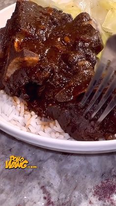 a plate with rice, meat and vegetables on it next to a knife and fork