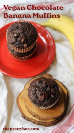 two chocolate banana muffins sitting on top of a red plate next to a banana