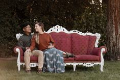 a man and woman sitting on top of a red couch