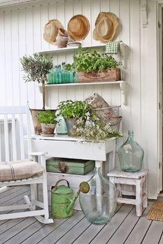 a white bench sitting on top of a wooden floor next to a shelf filled with potted plants