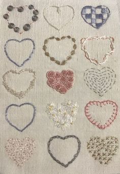 many different types of heart shaped beads on a white cloth with red and blue thread