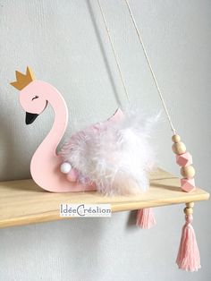 a pink flamingo with a crown hanging from it's back on a shelf