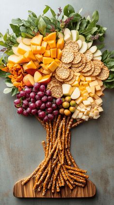 a wooden cutting board topped with grapes, apples and crackers