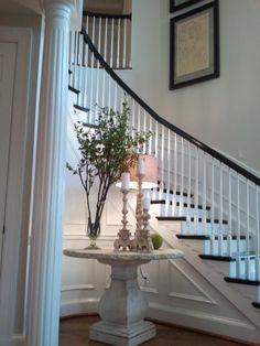 there is a vase with some flowers on the table in front of the stair case