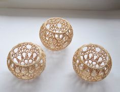 three gold filigrees sitting on top of a white table next to a lit candle