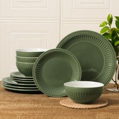 green dinnerware set on wooden table next to potted plant