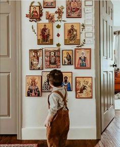 a little boy standing in front of a wall with pictures on it