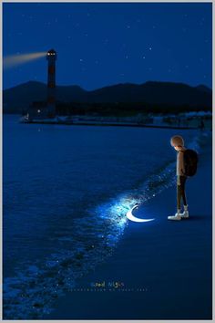 a person standing on the beach at night with a lighthouse in the background