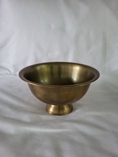 a brass bowl sitting on top of a white sheet