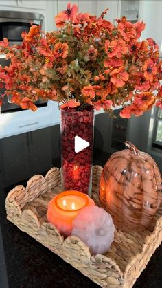 a vase filled with flowers and candles on top of a tray next to a candle