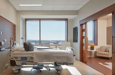 a hospital room with a bed, couch and table in it's center area