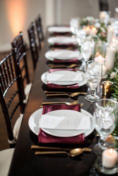 the table is set with white plates and silverware, red napkins and candles