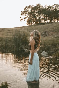 a woman standing in the water with her back to the camera