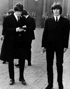 two men in suits and ties are walking down the street