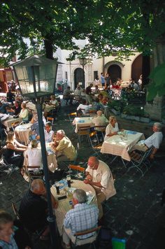 many people are sitting at tables outside eating