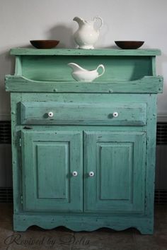 an old green cabinet with two bowls on top