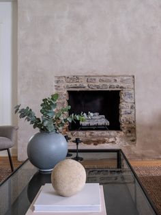 a living room with a fire place and vases on the coffee table in front of it