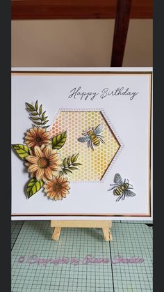 a birthday card with flowers and bees on it, sitting on top of a table