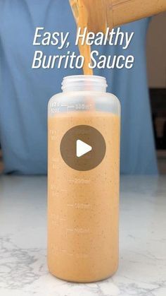 a person pours some liquid into a glass jar with the words easy, healthy burrito sauce