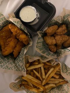 three baskets filled with chicken and french fries next to dipping sauce on top of them