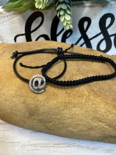 the black cord bracelet has a silver circle on it and is decorated with an evil symbol