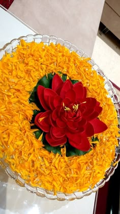 a cake with yellow and red flowers in it sitting on a table next to a glass bowl