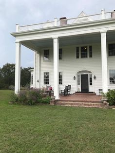 a large white house sitting on top of a lush green field