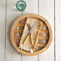 there is a wooden tray with two knives and a brush in it on the table