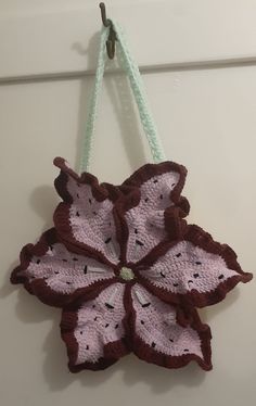 a crocheted flower hanging from a hook on a wall with string attached to it