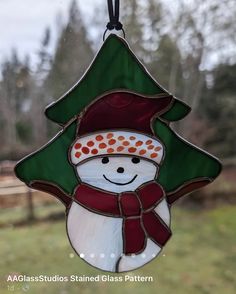 a stained glass snowman ornament hanging from a window