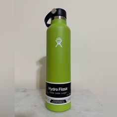 a green hydro flask water bottle sitting on top of a white counter next to a wall