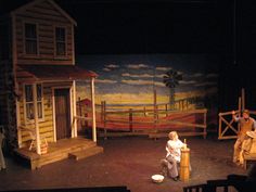 two people sitting on stage in front of a painted wall and wooden fenced area