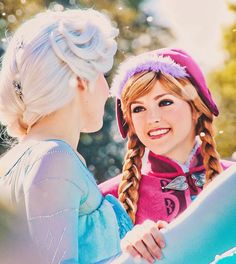 two girls dressed as disney princesses talking to each other