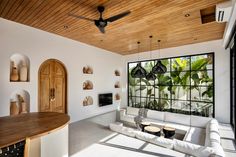 a living room filled with white furniture and wooden ceilinging next to a large window