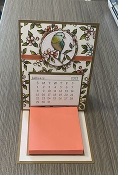 a desk with a calendar on it and a bird sitting on top of the card