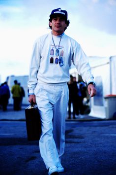 a man walking down the street carrying a briefcase and wearing a sweatshirt with pictures on it