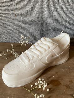 a pair of white nike sneakers sitting on top of a wooden table next to flowers