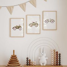 three framed pictures hang on the wall above a wooden shelf with toys and decorations in front of it