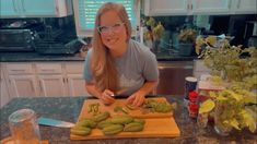 a woman cutting cucumbers on top of a wooden cutting board in a kitchen